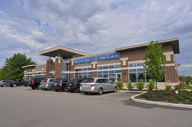 A row of cars are parked in front of a large building.
