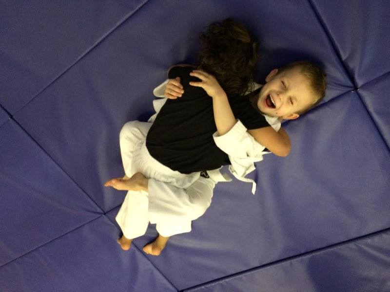 A boy and a girl are wrestling on a purple mat