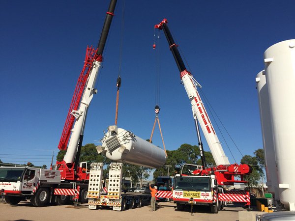two cranes lifting tube
