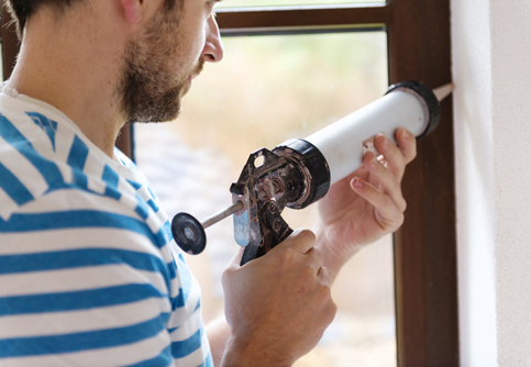 Man applying silicone sealant in a window