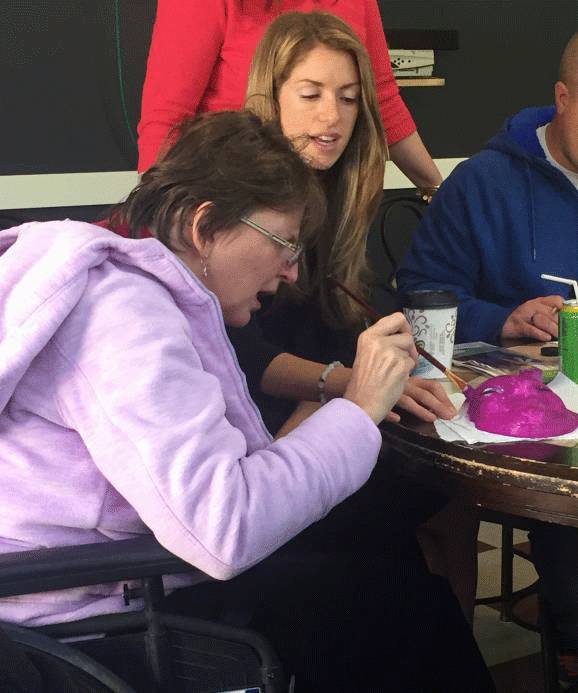 A woman in a wheelchair is painting with a brush