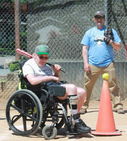 A man in a wheelchair is holding a baseball bat
