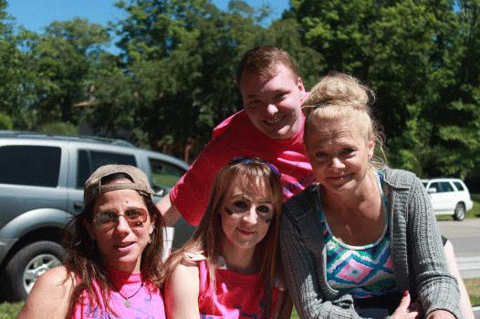 A group of people posing for a picture in front of a car.