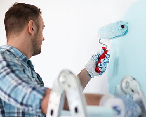 man painting walls blue in Londonderry