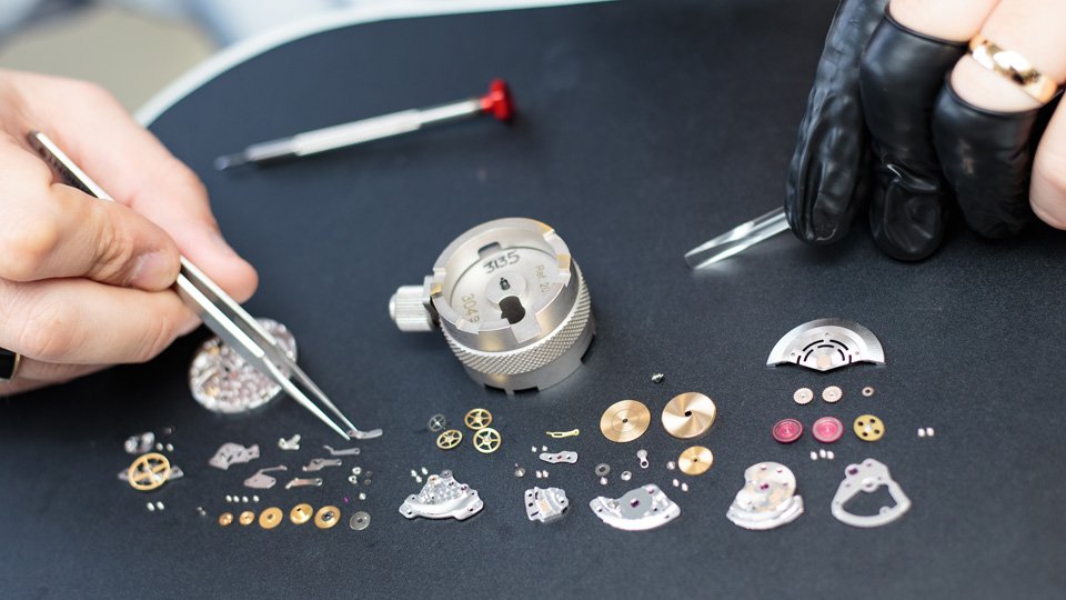 man picking up tiny watch parts