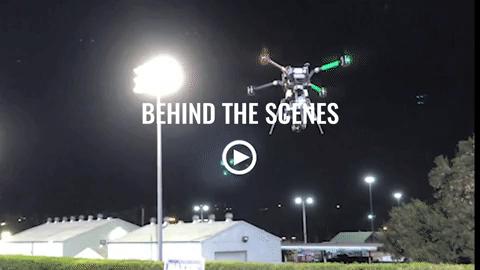 A drone is flying in the night sky with the words behind the scenes above it