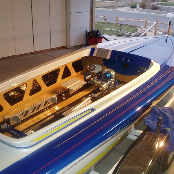Blue-and-white speedboat with exposed engine in a garage, seen from above