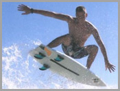 Surfer riding a wave on a white surfboard under a blue sky