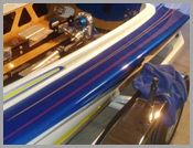 Close-up of a blue and white striped boat hull with metal fittings and a folded blue cloth nearby