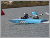 Blue speedboat numbered 222 racing on choppy water with a driver onboard