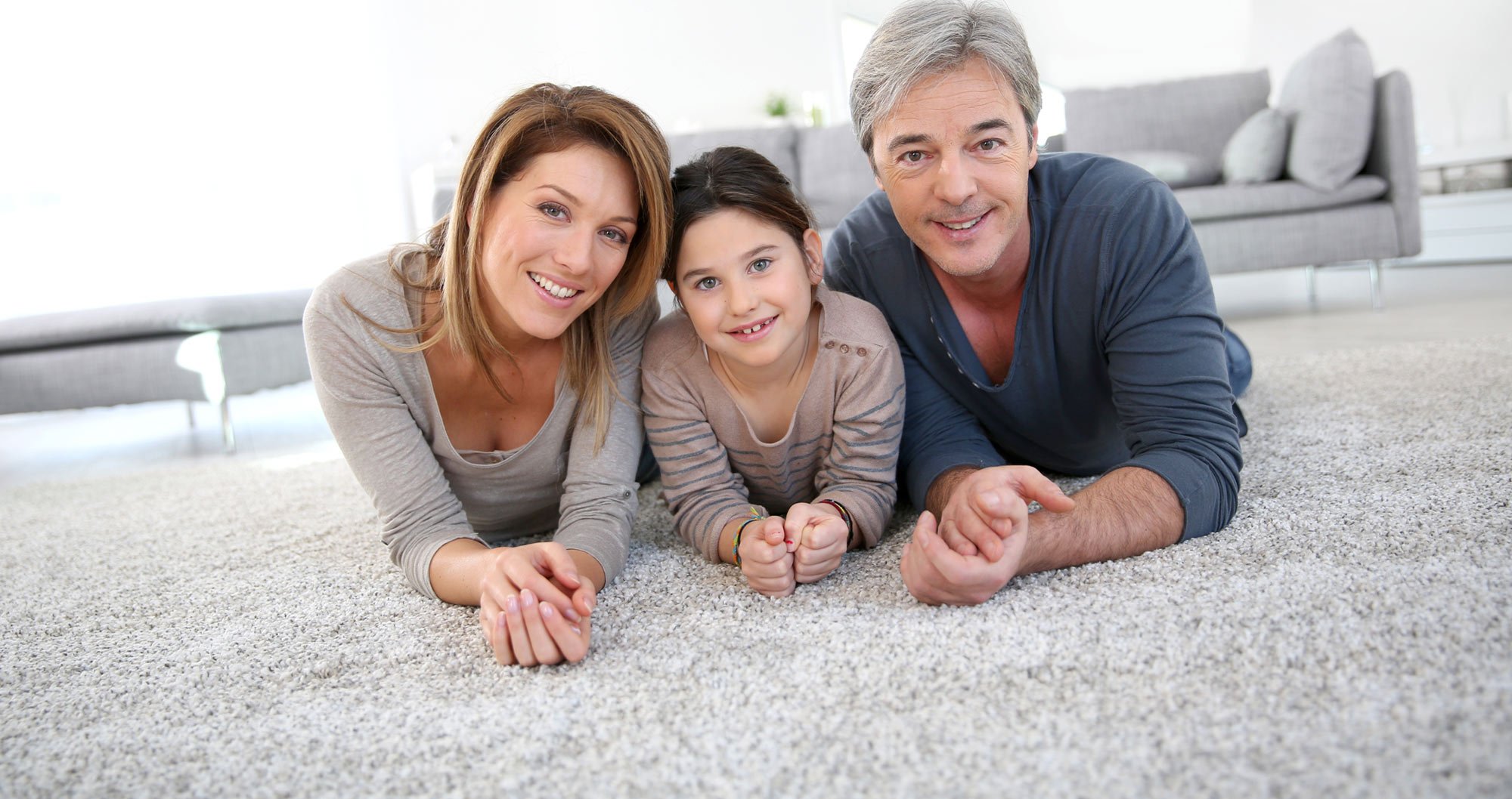 Young couple with their daughter lying on a clean carpet 