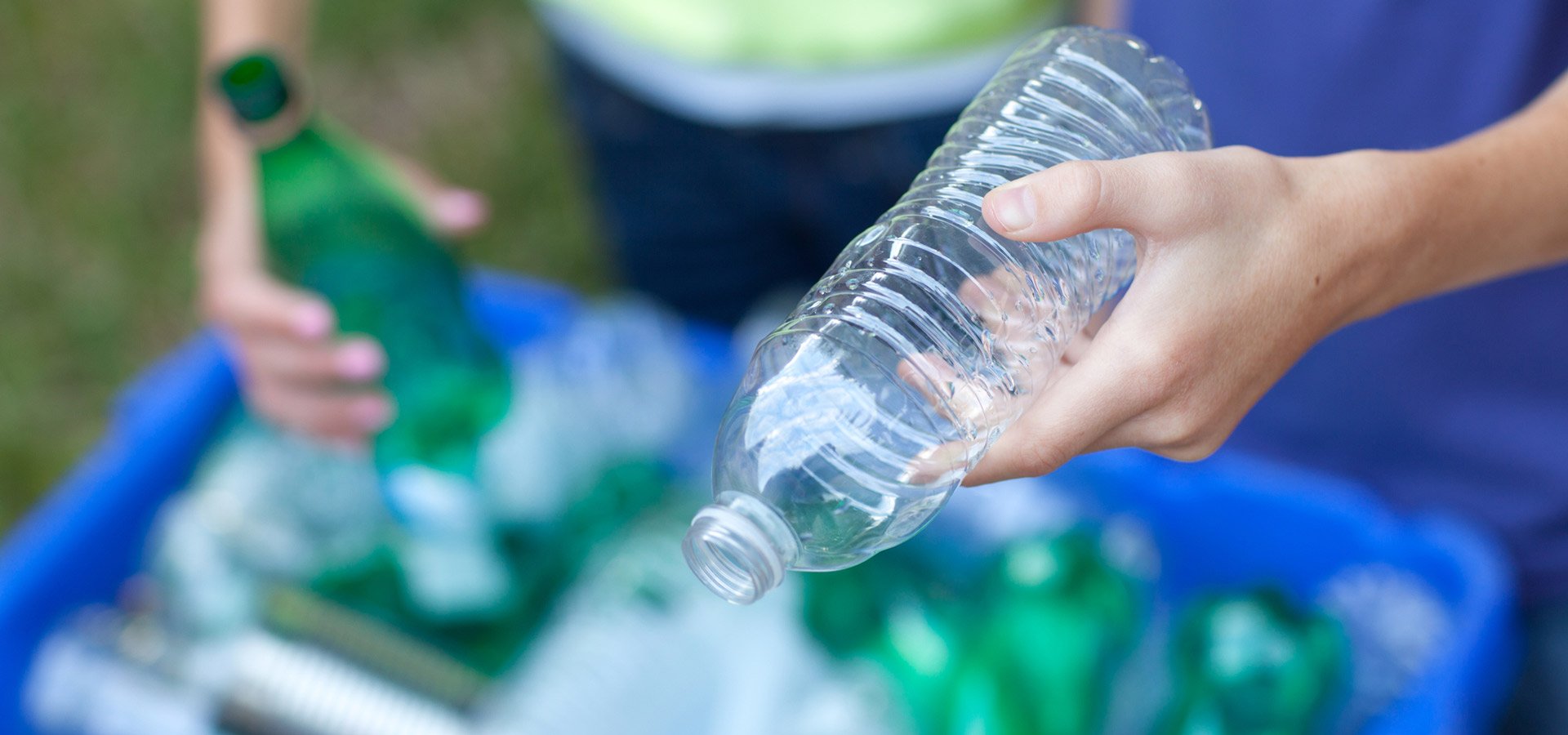 lightning bin hire boy and girl putting clear and green bottles and metal cans in recycling blue bin outside in yard