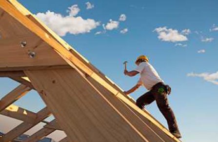 builder-frame-work-sky Timber roof trusses being installed in Shoalhaven